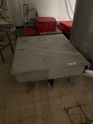 une table en métal au milieu d'une pièce, avec des draps rouges étalés sur le sol