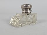 a small glass bottle with a silver top on a white surface