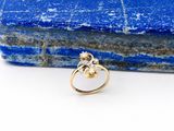 un gros plan d'une bague en or sur laquelle est sertie une pierre bleue