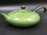 une théière verte posée sur une table