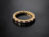 a gold ring with ruby stones on a black surface