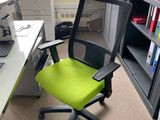a green office chair sitting in front of a computer desk