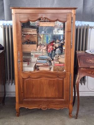 a wooden cabinet with a glass door in the corner of a room