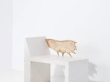 un banc blanc sur lequel est posé un animal en bois, dans une pièce blanche