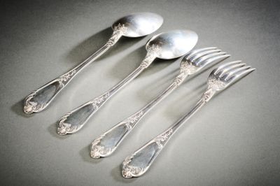 quatre cuillères en argent et une fourchette sont alignées sur une table
