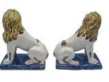 pair of ceramic lion bookends with golden manes on blue base