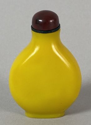 a yellow vase with a red lid sitting on a table