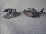 pair of silver plated fish figurines on a gray cloth