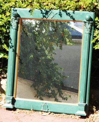 un miroir posé par terre devant des buissons