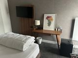 a bed with a white comforter and a wooden desk in the corner of the room