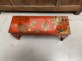 a red table with a painting on it in the middle of a room