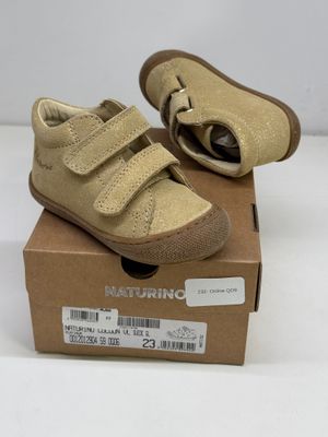 des chaussures de petit garçon dans une boîte posée sur une surface blanche