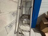 une échelle métallique appuyée contre un mur, à côté d'un carton