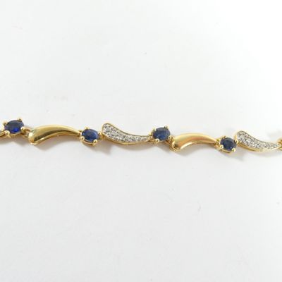 un gros plan sur un bracelet en or orné de pierres bleues et blanches