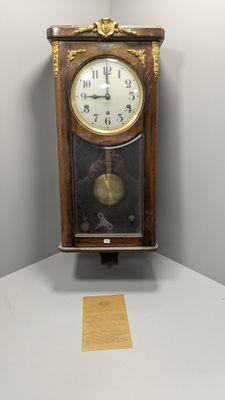 une horloge dans un coin d'une pièce où il y a un bout de papier par terre