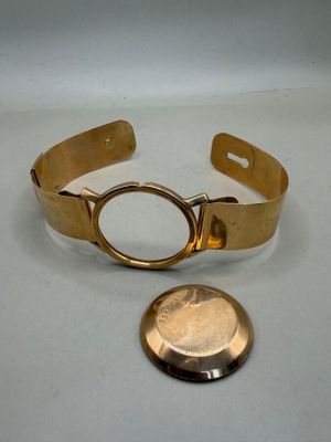 bracelet plaqué or, avec une pièce posée sur une table à côté