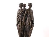 statue en bronze représentant deux femmes debout l'une à côté de l'autre sur une surface blanche