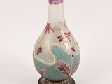 un vase en verre avec un couvercle violet, posé sur un socle