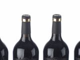 six bottles of wine lined up in a row on a white surface