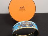 une boîte orange sur laquelle est posé un bracelet bleu et doré, posée sur une surface noire