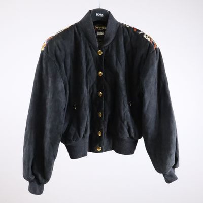 a black jacket hanging on a hanger on a white wall