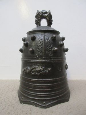 a large metal bell sitting on the floor next to a white wall
