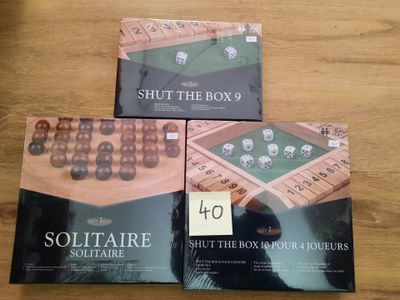 trois boîtes de jeux « Shut the Box » posées sur une table