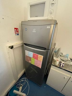 une photo d'une cuisine avec un réfrigérateur et un micro-ondes