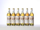 four bottles of white wine are lined up on a table