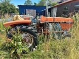 un tracteur orange qui est garé dans l'herbe