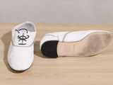 pair of white shoes with black soles sitting on a wooden table