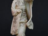 statue of a woman in a kimono outfit holding a fan and a bird