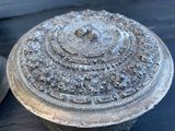 une boîte en argent posée sur une table, à côté d'une bougie