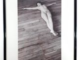 framed photograph of a nude woman laying on a wooden floor
