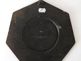 a black plate hanging on a wall on a white wall