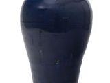 un vase bleu posé sur une surface blanche