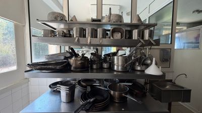 many pots and pans sitting on a shelf in the kitchen