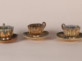 three small cups and saucers sitting on top of a table