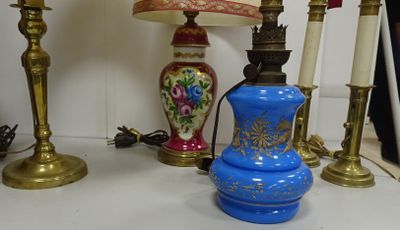 un vase bleu posé sur une table, à côté de deux bougies dorées