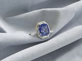 un gros plan d'une bague ornée d'un saphir bleu posée sur un tissu blanc
