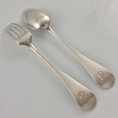 two silver spoons and a fork on a table