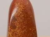 a brown vase sitting on top of a wooden table next to a white wall