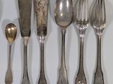 a lot of silver spoons and forks on the table