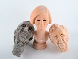 three clay sculptures of a woman and a bird on a table
