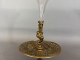 a gold plate with a glass vase on top of it