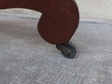a small wooden chair with wheels on the floor