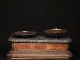 two bowls on top of a wooden stand with a black background