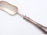silver plated serving spoon with ornate handle on a white surface
