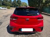 a red car parked in a parking lot with trees in the background