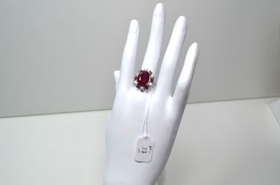 une main de mannequin blanche ornée d'une bague rouge